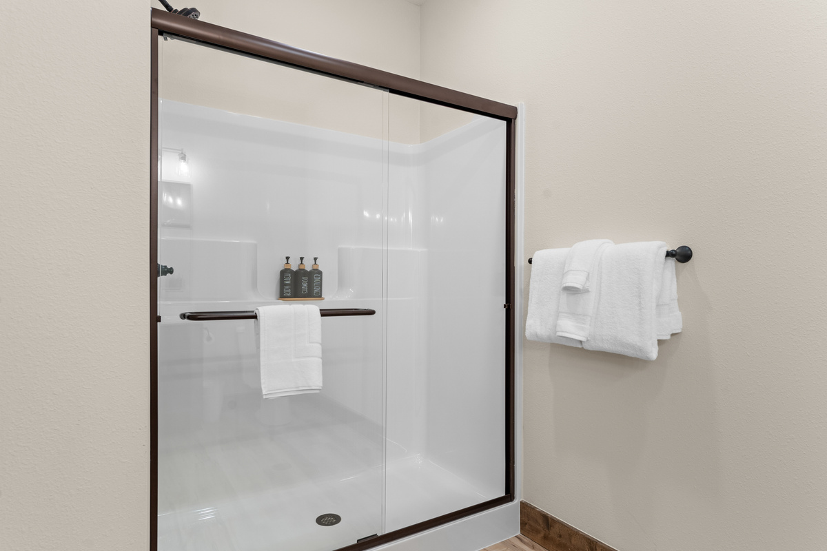 Step into a bright glass walk-in shower with plush towels within reach.