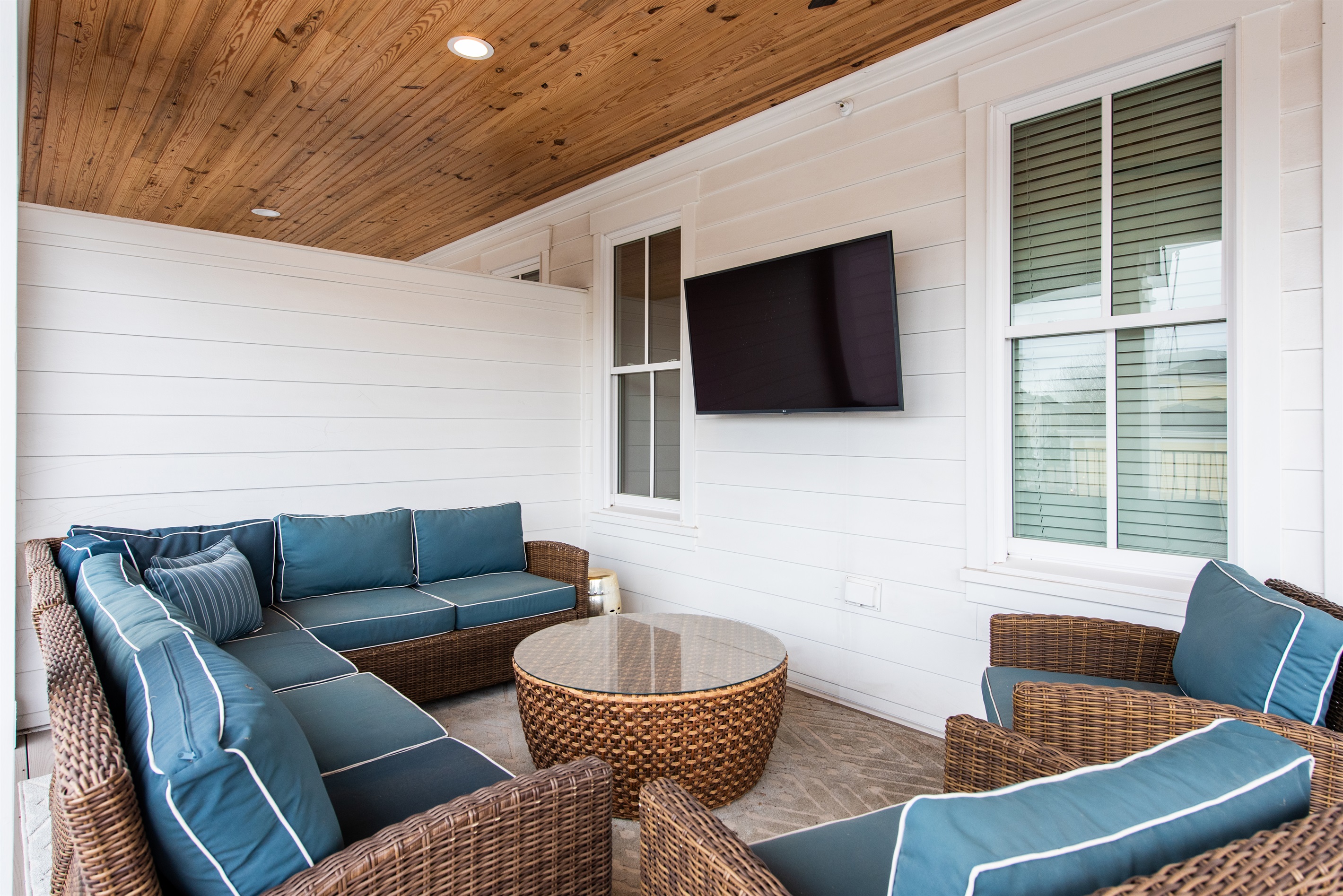 **Cozy Outdoor Lounge with Entertainment:** Relax in this inviting covered patio space, featuring plush wicker seating, a round coffee table, and an entertainment-ready TV. Ideal for unwinding or socializing after exploring the Bourbon Trail.
