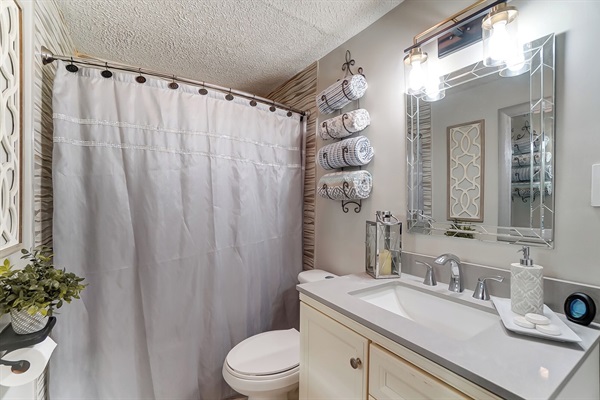 The tub/shower has a grab bar and floor mat.