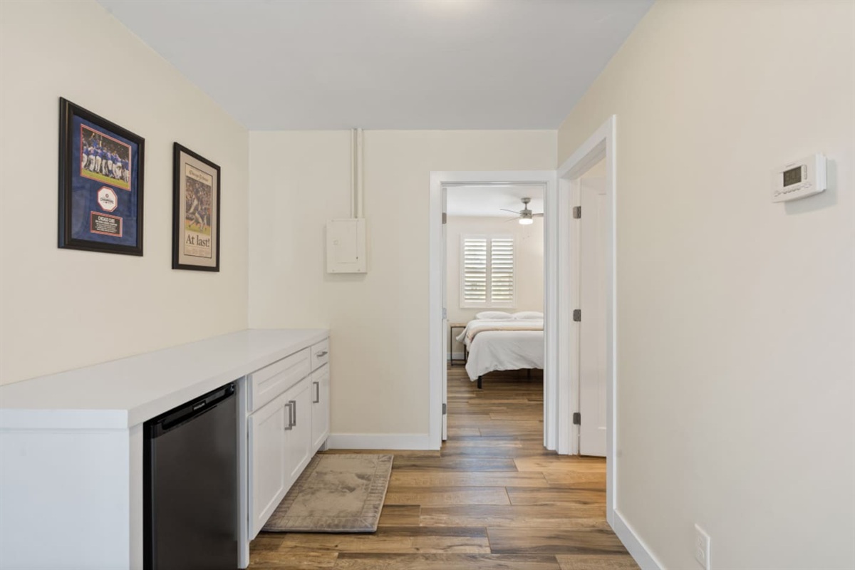 Hallway with built-in beverage fridge, extra cabinet storage, and easy access toward the nearby bedroom.
