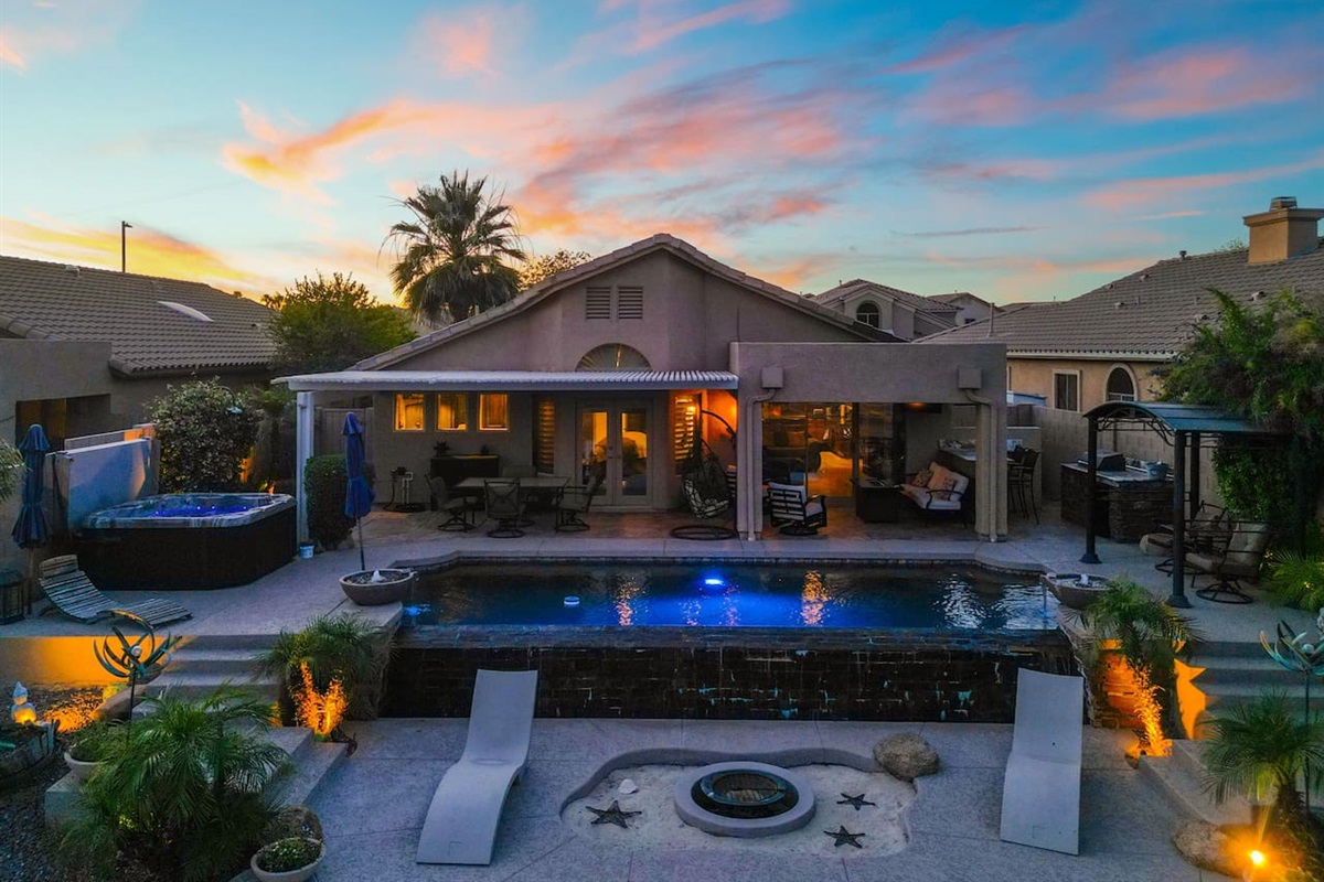 As the day fades, the backyard transforms — pool lights shimmer, landscape lighting glows, and the covered patio invites you to linger long into the warm Arizona night.