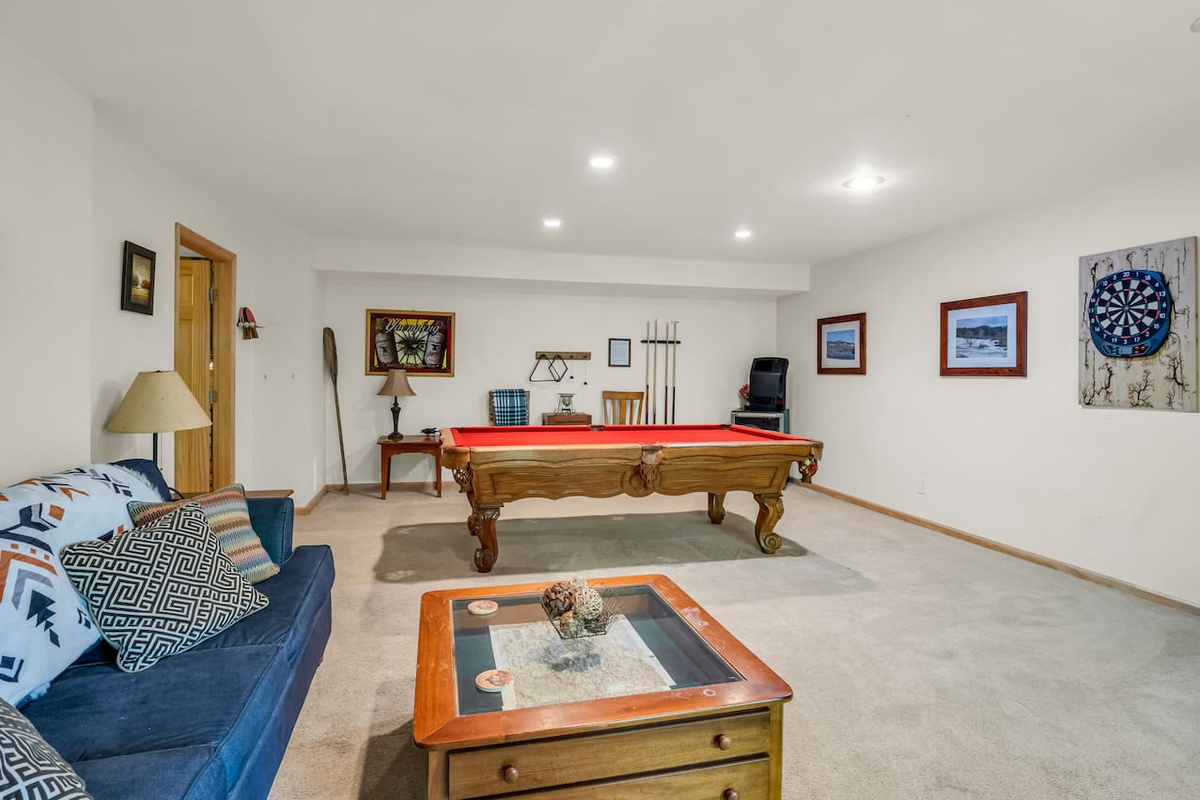 Basement with seating, pool table, dart board, variety of board games, and television