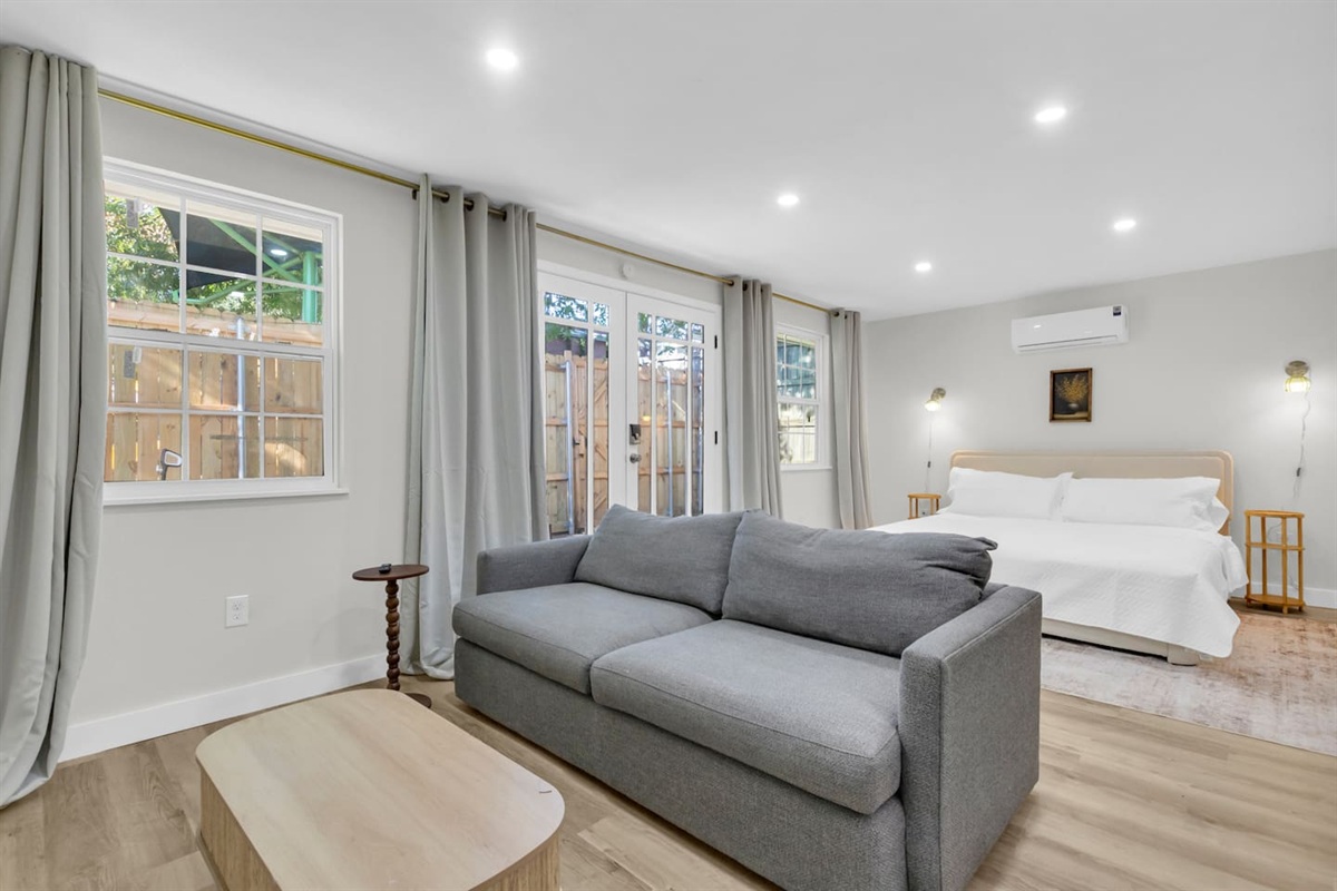 Spacious 500 sq ft open-concept studio with king bed, room-darkening blinds, spacious couch, TV, full kitchen, Keurig coffee maker, Wi-Fi, and in-unit washer/dryer—ideal for short or long-term stays.