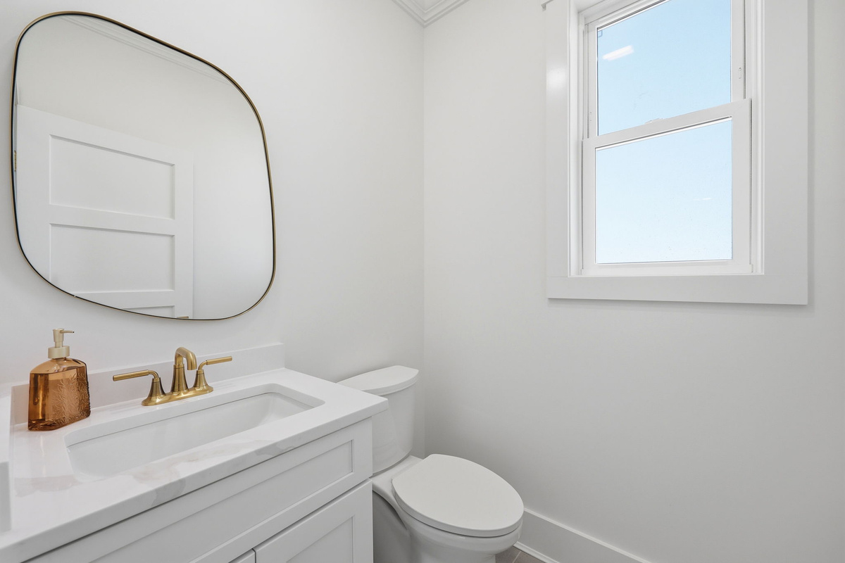 Modern bathroom featuring elegant gold fixtures and a clean minimalist coastal design