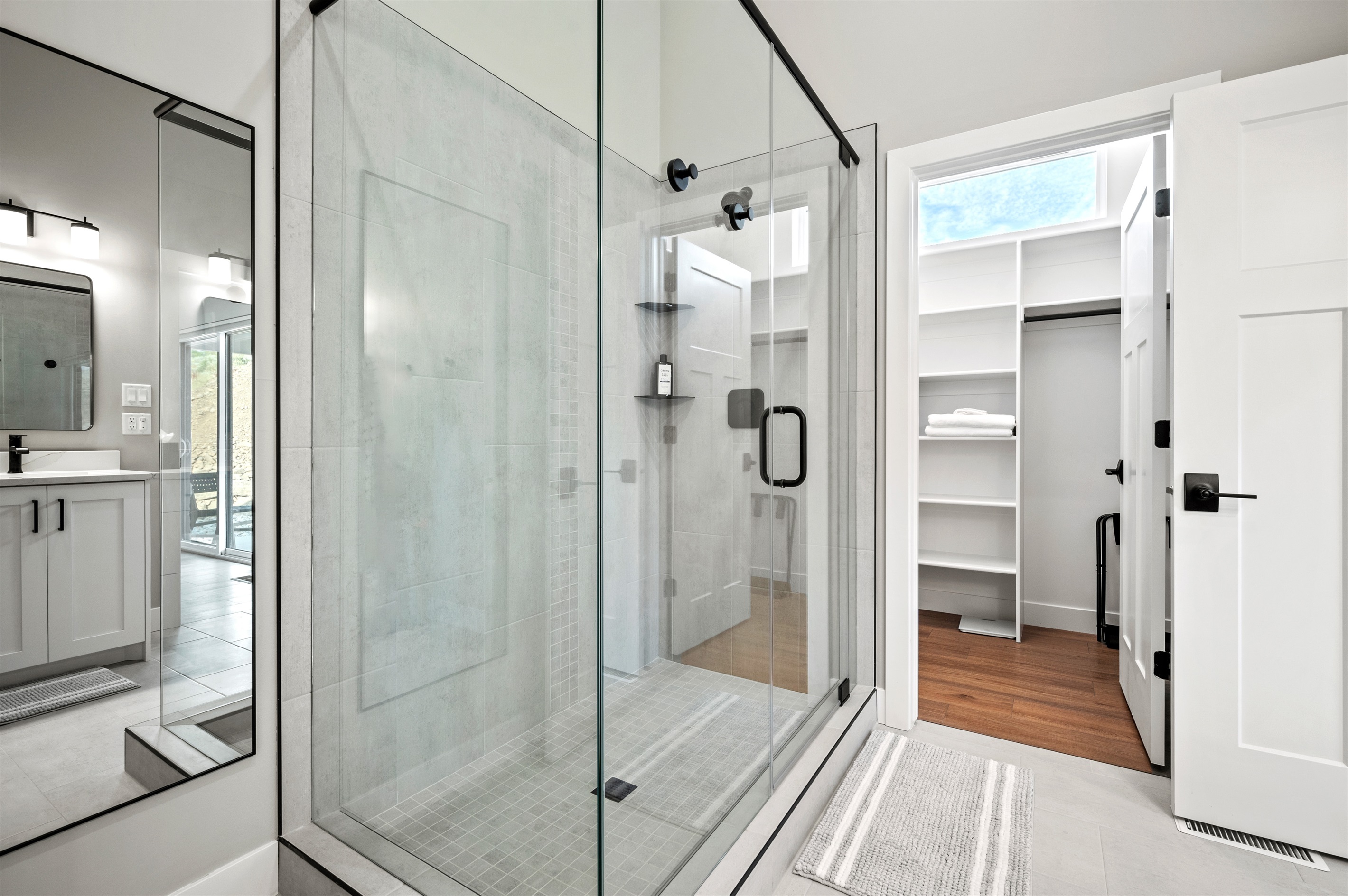 Opposite the dual sinks, a large glass shower awaits, along with a spacious walk-in closet.
