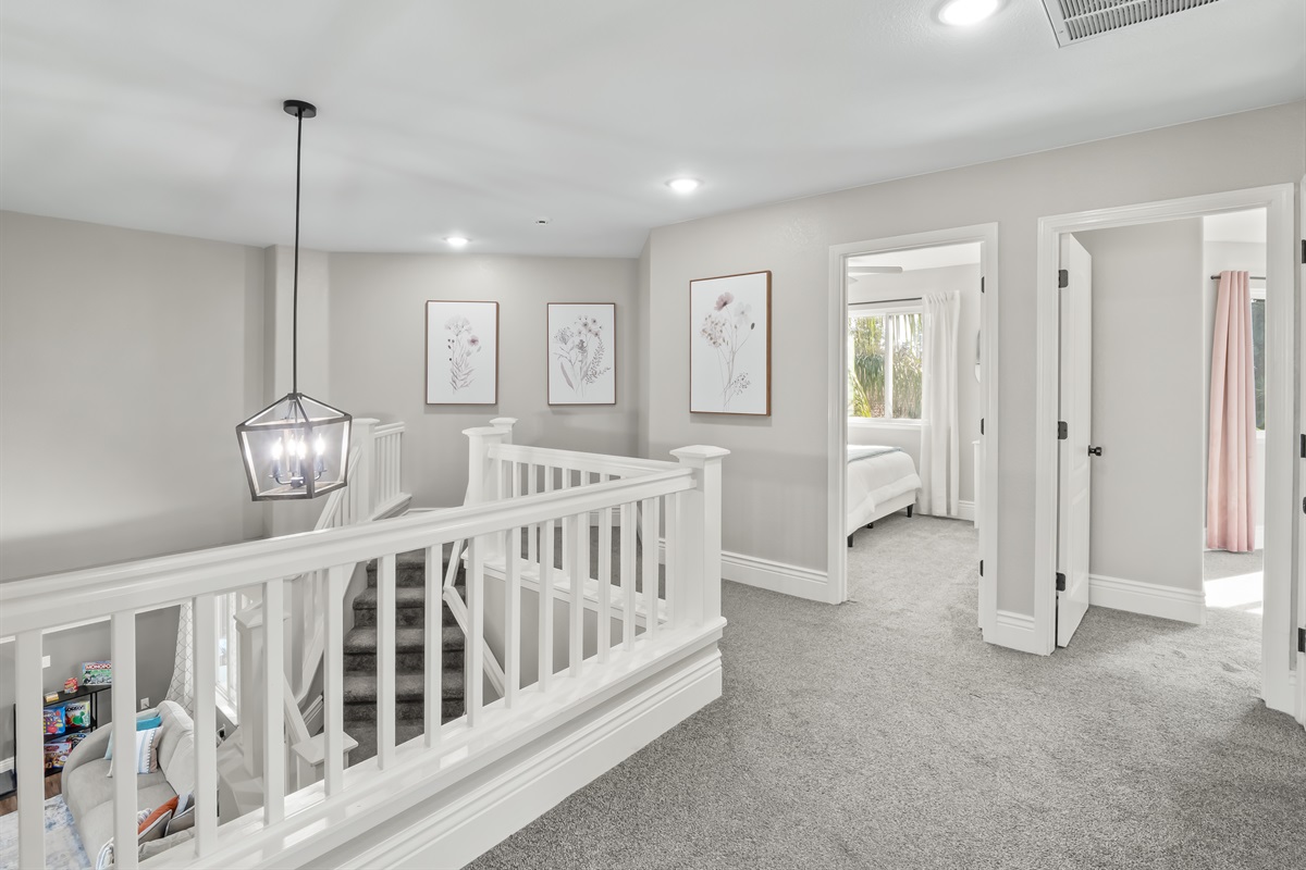 Light-filled upper-level corridor with elegant railing, designer lighting, and soft neutral tones—enhancing the home’s open layout and upscale feel.