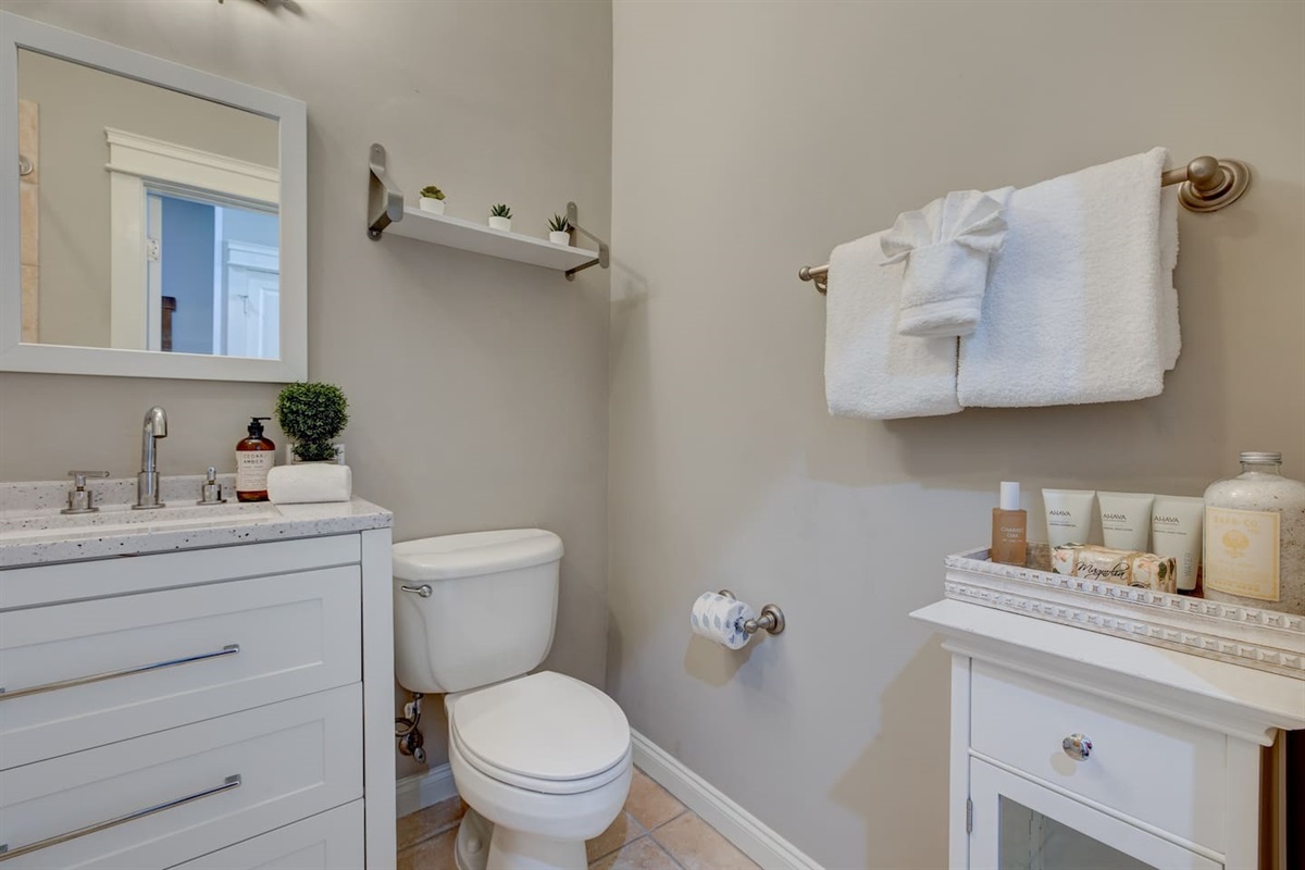 Full bathroom with toilet, sink, storage for bath linens, and a tiled shower-tub combo.