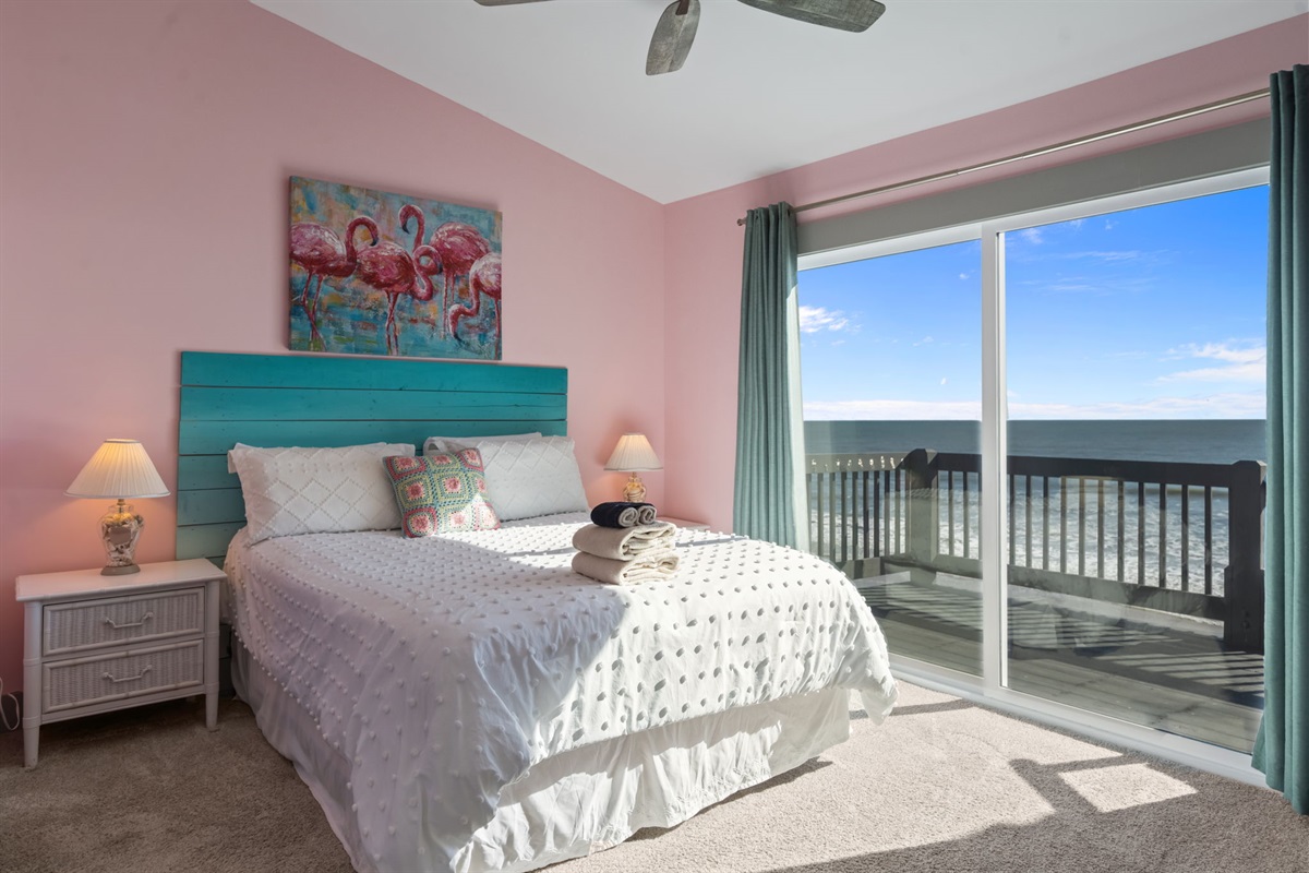 Wake up to stunning ocean views in this serene master bedroom, featuring a cozy bed, soft coastal d&eacute;cor, and sliding glass doors that open directly to the balcony