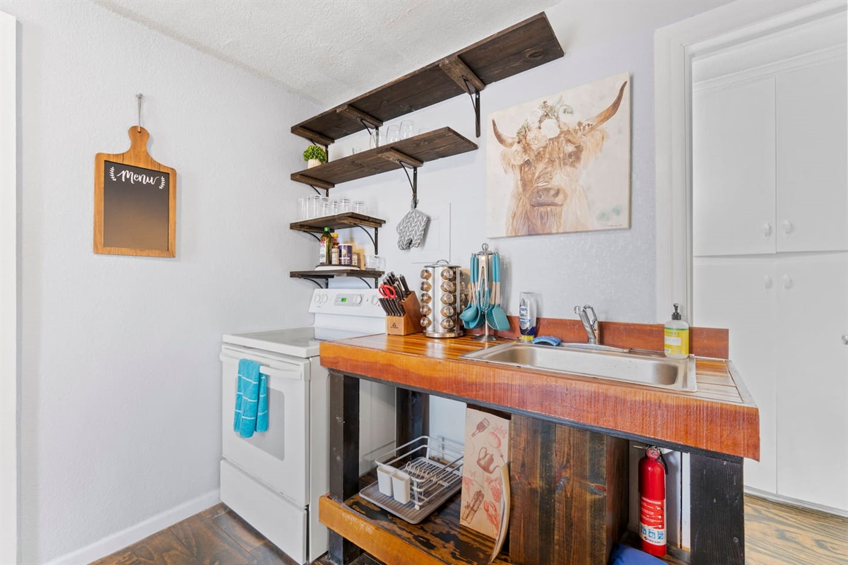Modern stove with open shelving above for easy access to kitchen essentials, and a sink stocked with supplies for your convenience.