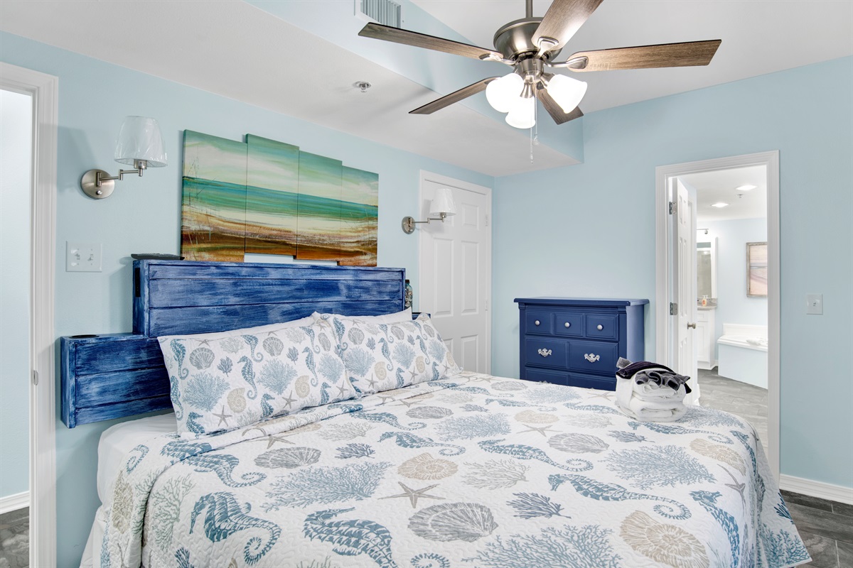 Primary Bedroom has a King bed with built in side tables, ceiling fan, wall mounted smart TV, chest of drawers and en-suite bathroom