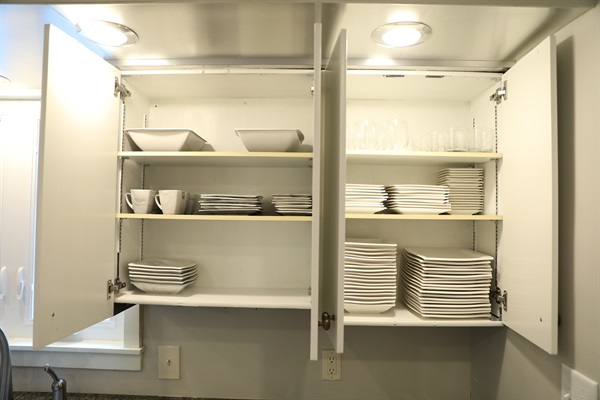 Kitchen cabinet showing plates, cups, and bowls