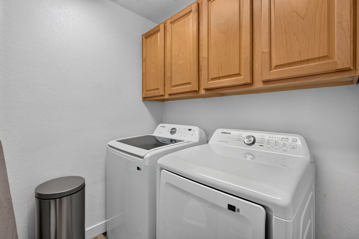 In- unit laundry area with washer, dryer, and overhead cabinet storage for added convenience during your stay.