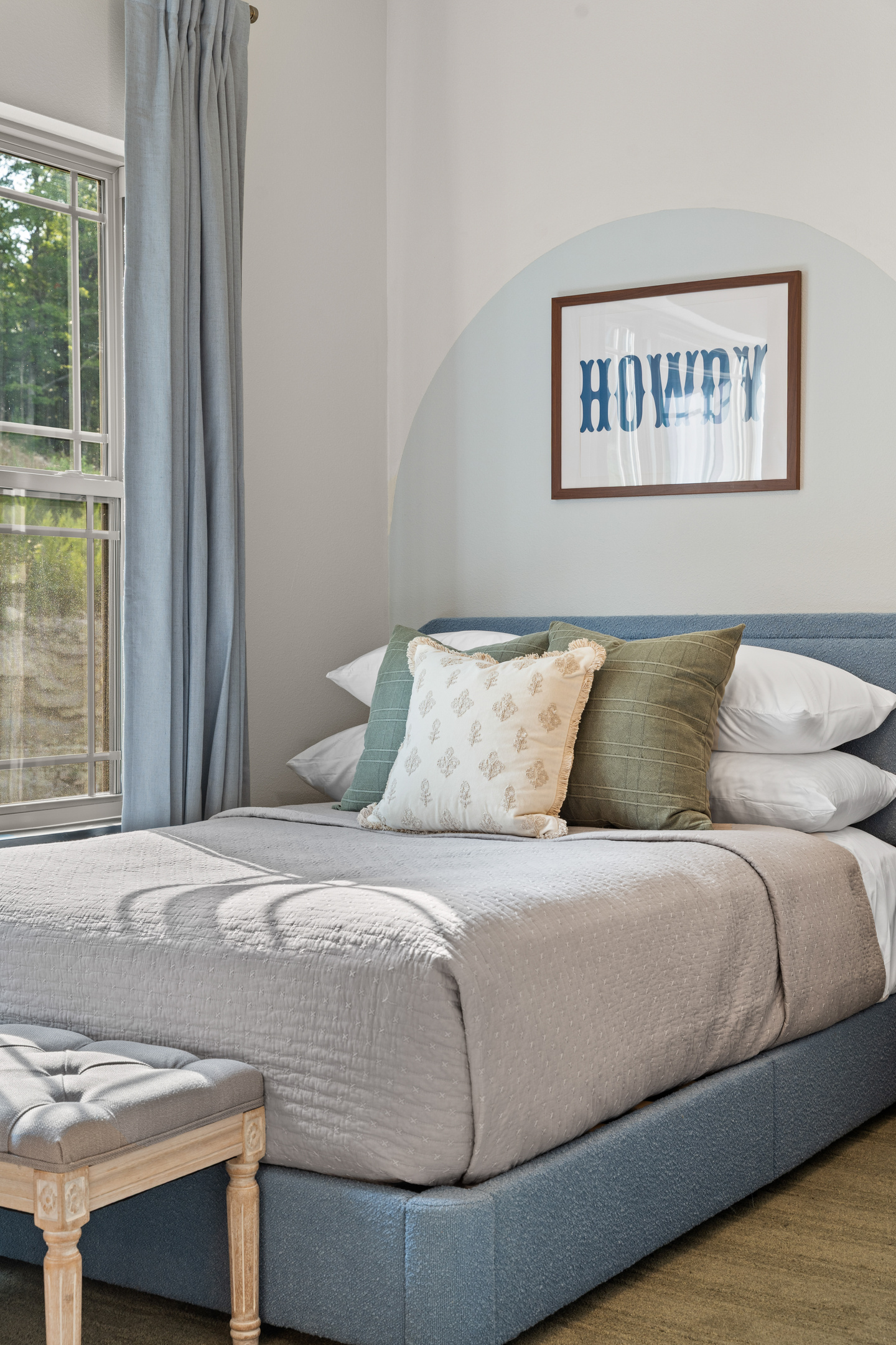 Soft greens and a blue upholstered bed keep the Austin Twin Room bright and restful.