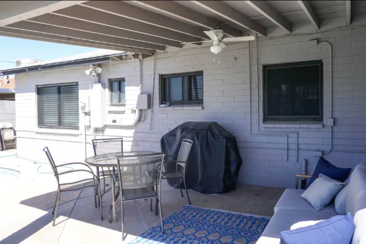 Covered back paiio with outdoor furniture and BBQ.
