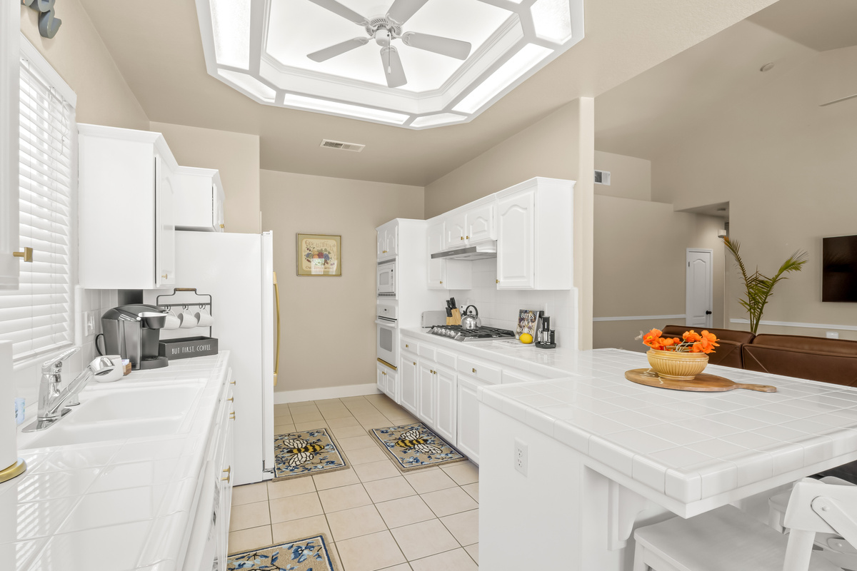 This spacious kitchen features ample cabinetry, extensive countertop space, full-size appliances, and a large island with seating.