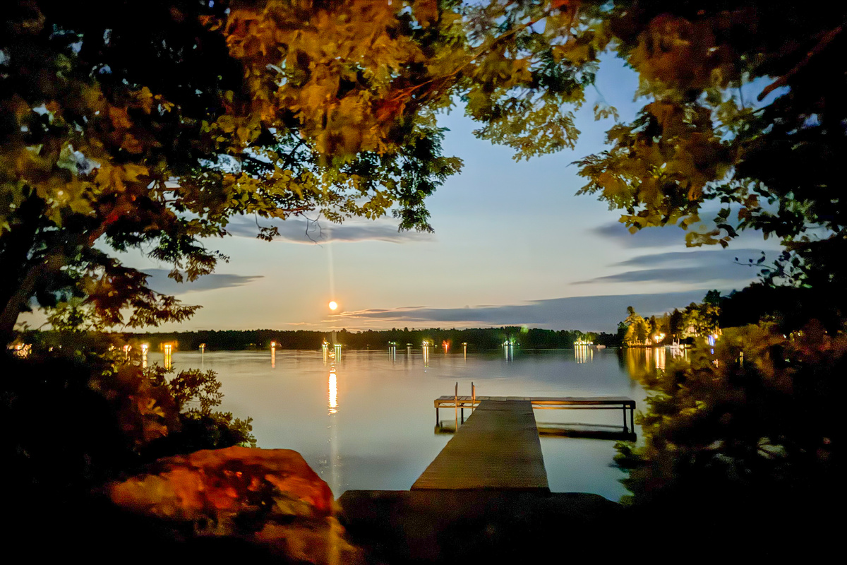 Moonlit waters from the dock landing at Loonrise Point! Exterior grounds lighting casts a warm glow over the granite entrance while the moon shines across Beech Hill Pond. Unwind after dark on your private peninsula in Otis, ME.