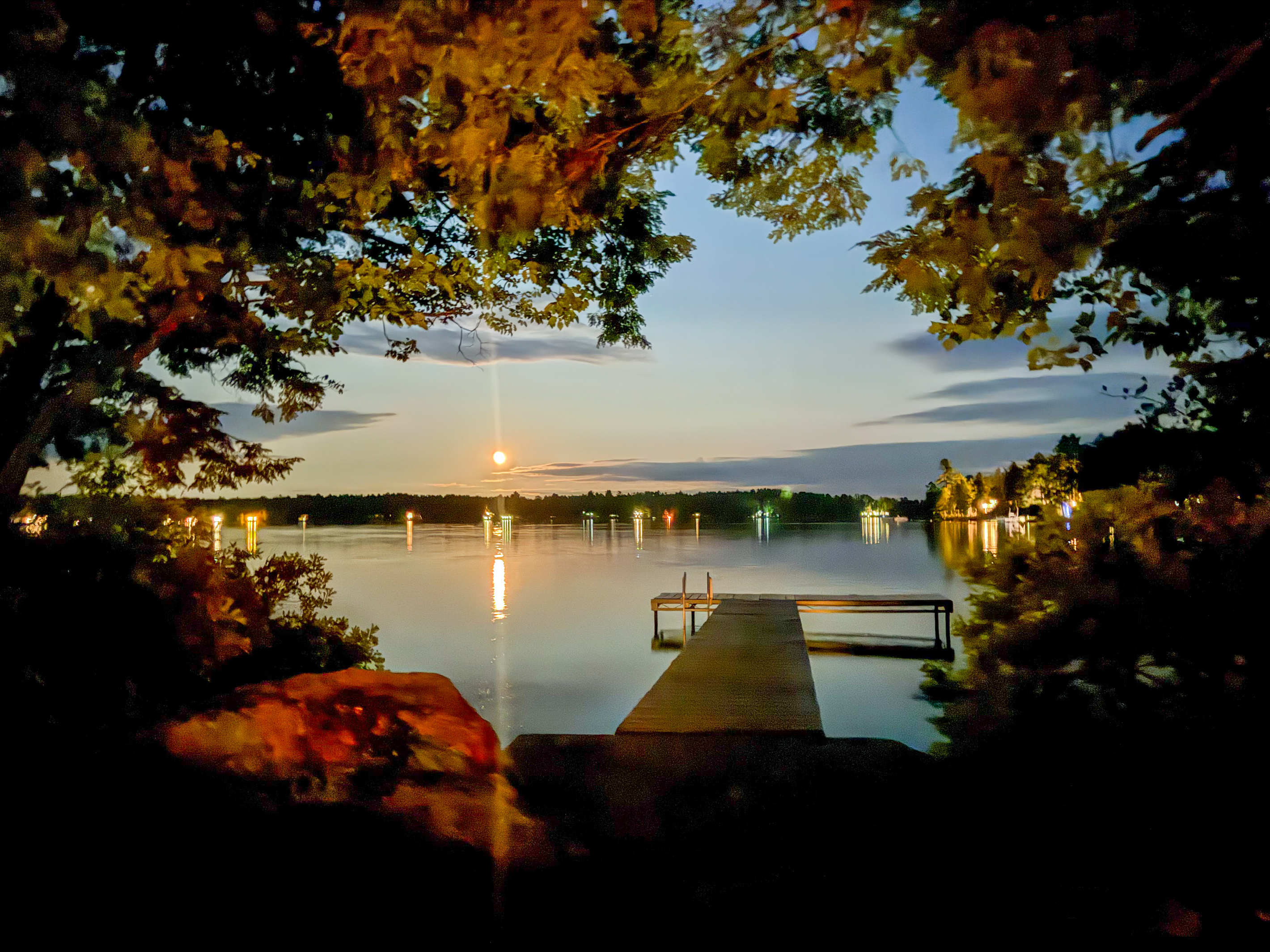 Moonlit waters from the dock landing at Loonrise Point! Exterior grounds lighting casts a warm glow over the granite entrance while the moon shines across Beech Hill Pond. Unwind after dark on your private peninsula in Otis, ME.