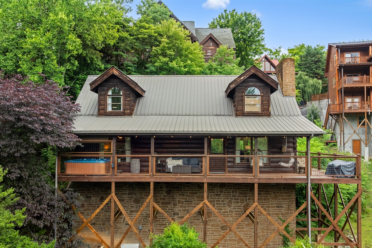 Enjoy the outdoors from the spacious covered deck featuring a private hot tub, comfortable conversational seating, and two cozy hanging basket chairs