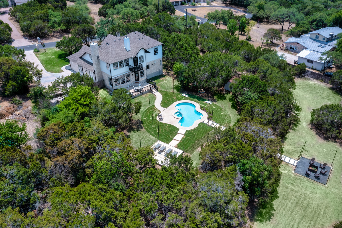 Bird's-eye view of the pool, patio, and lush surrounding landscape.