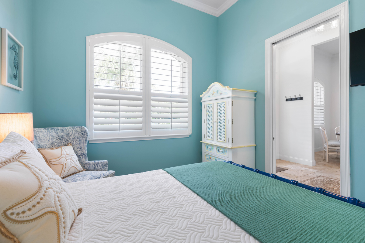 Painted armoire gives the Turquoise room extra storage, and the arched window fills it with soft natural light.