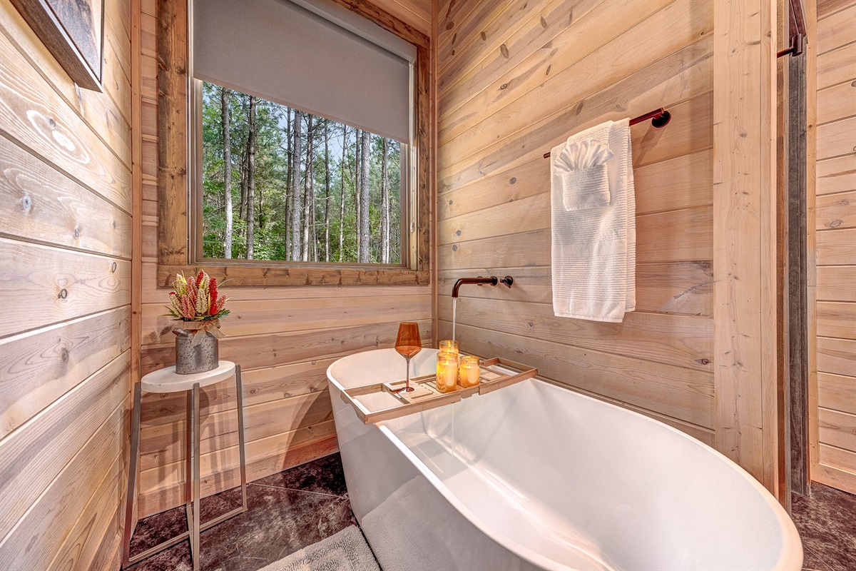 Soak away your cares in this deep freestanding tub with tranquil forest views.