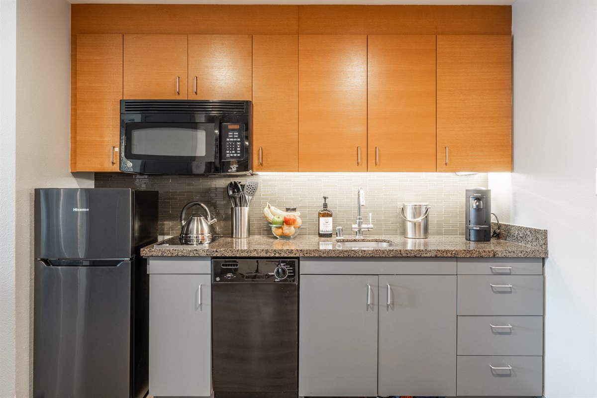 The well-equipped efficiency kitchen features an upgraded and larger refrigerator with dedicated freezer, dishwasher, two burner cooktop, and mircorwave.