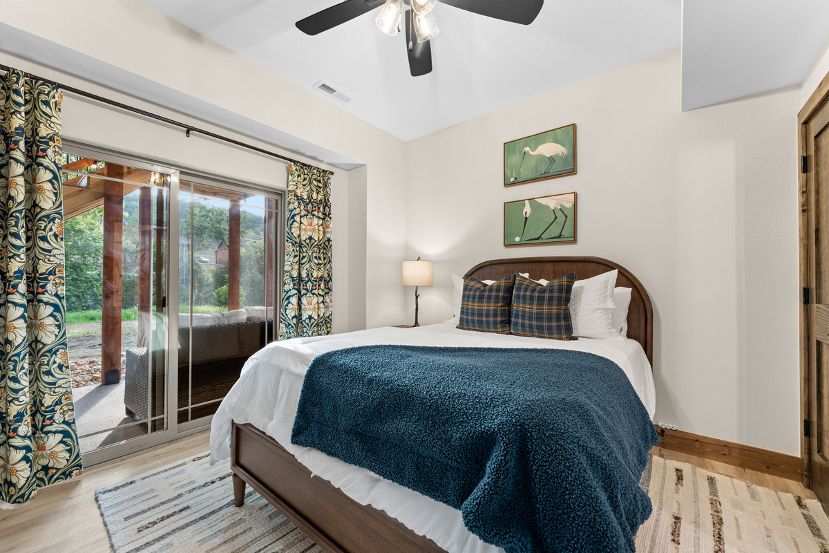 A walkout queen suite in deep blues with whimsical heron-golf prints and a slider to the trees.