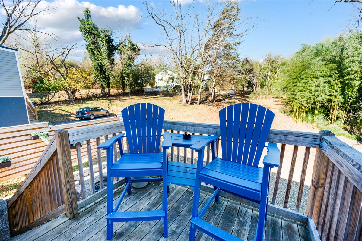 The private backyard offers a cozy back porch with a bistro table, fire pit, solar lights, and four Adirondack chairs—perfect for relaxing evenings.