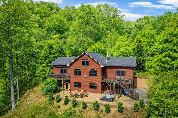 A panoramic view of the home, showcasing private outdoor spaces with hot tub, sauna, and fire pit—designed for gathering, relaxing, and taking in the mountains.