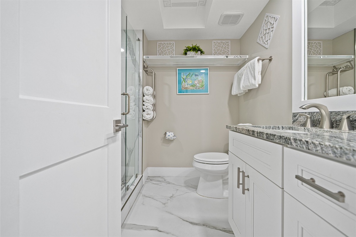 The master bath is a quiet, well appointed space with marble tile underfoot, a granite vanity, and a glass shower that gives the whole room a calm, hotel-quality feel from the moment you walk in.