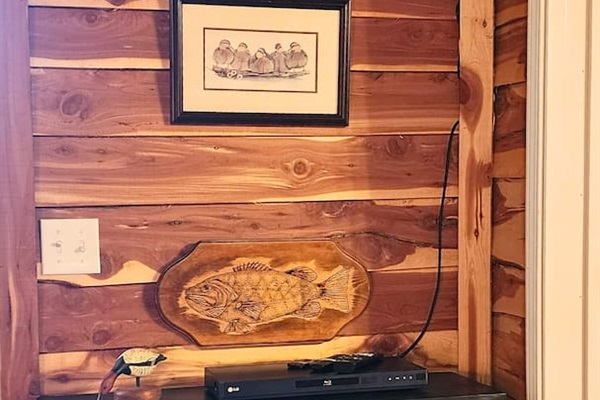 The lodge’s electric fireplace adds a warm, flickering glow and rustic charm to your stay. Framed by stacked stone and topped with fishing-themed decor, it’s the perfect spot to unwind after a day of hiking, fishing, or simply relaxing in nature.