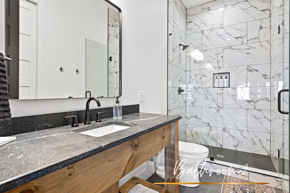 Sleek lines and contrasting textures make this bathroom a modern haven, highlighted by striking black fixtures and marble-esque walls.