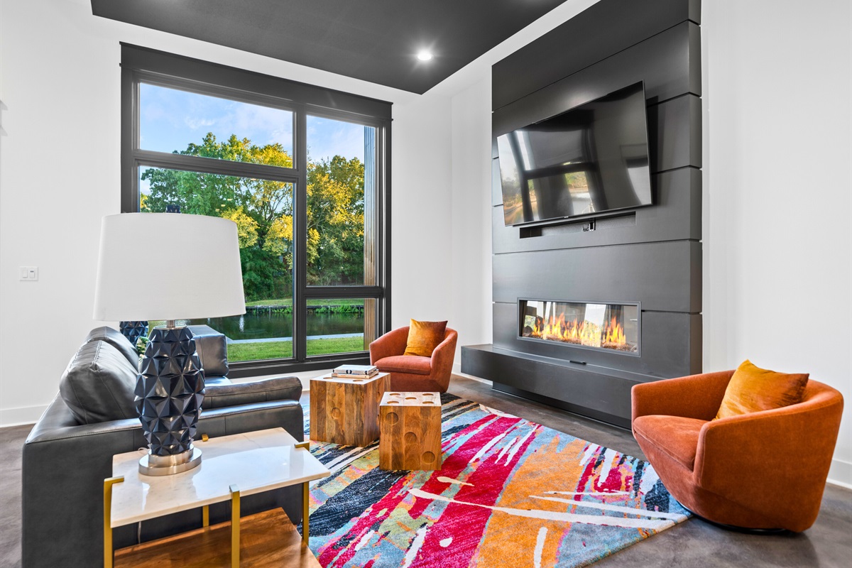 Floor-to-ceiling windows brighten this cozy corner, where modern furniture and pops of color create a fun yet sophisticated vibe.