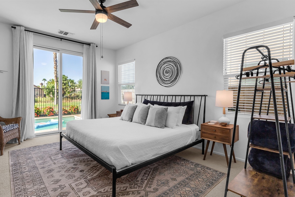 Spacious primary suite with serene golf-course and pool views through sliding glass doors