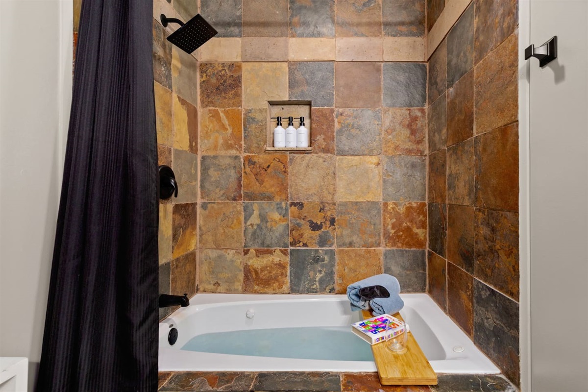 Relax & recharge. Ensuite bath with jacuzzi jets, bath shelf, and stocked essentials.
