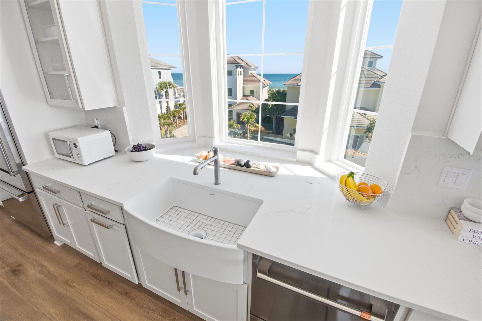 You rinse sandy hands at the farmhouse sink while the kids peek out for their first glimpse of the ocean. Snacks get prepped, towels get folded, and the next beach run is already being planned—sunlight and sea views included.
