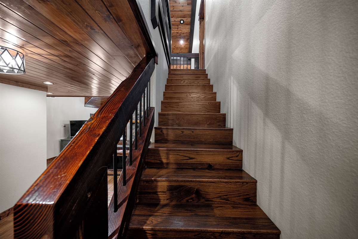 Wooden staircase leads to two upper bedrooms and game room
