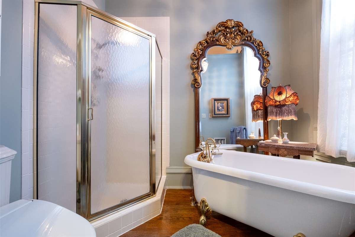 Private bathroom with clawfoot bubble bathtub, glass-enclosed shower, Japanese-style bidet toilet, and elegant vintage-style fixtures