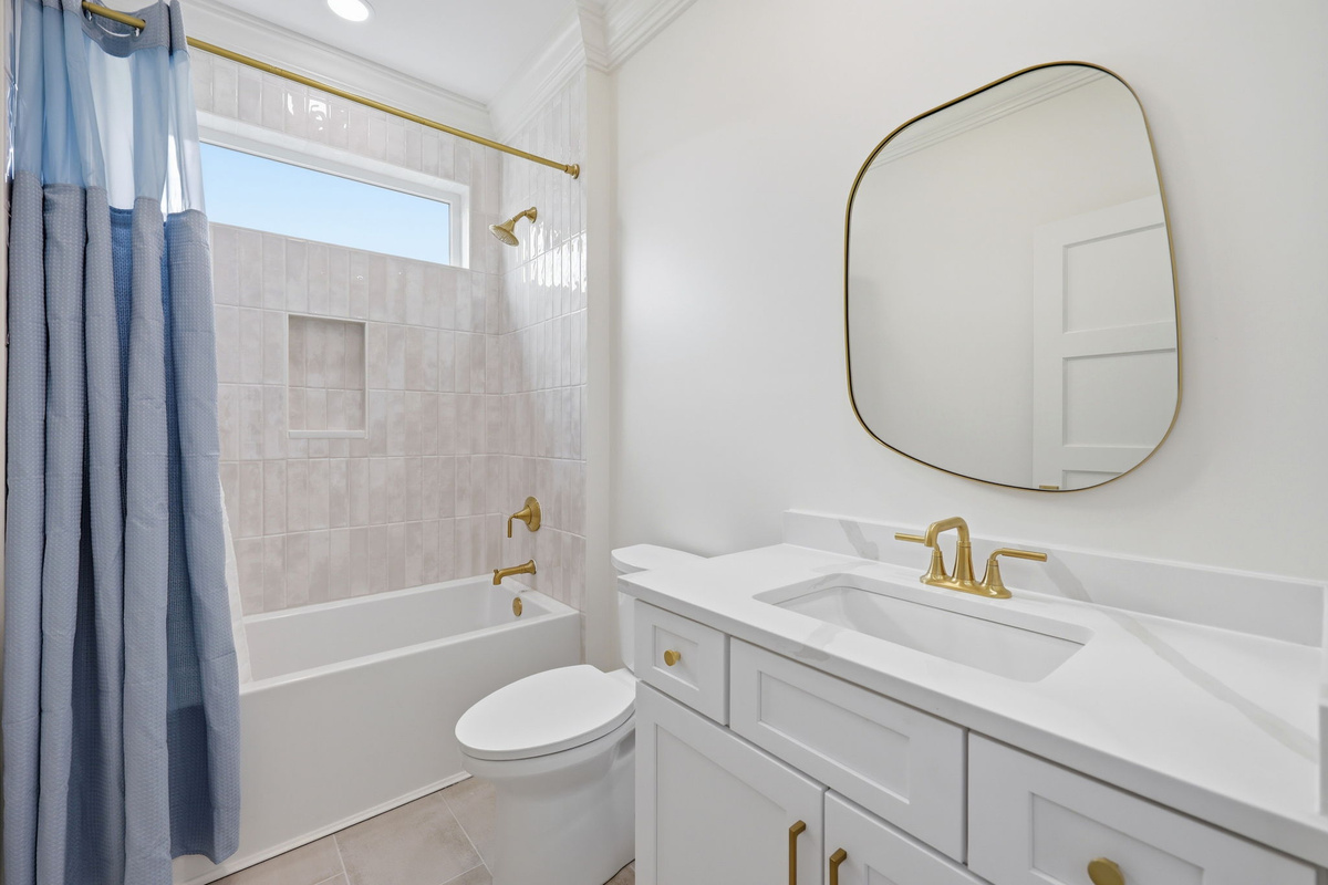 Walk-in glass shower with marble-style tile and gold rainfall shower fixtures