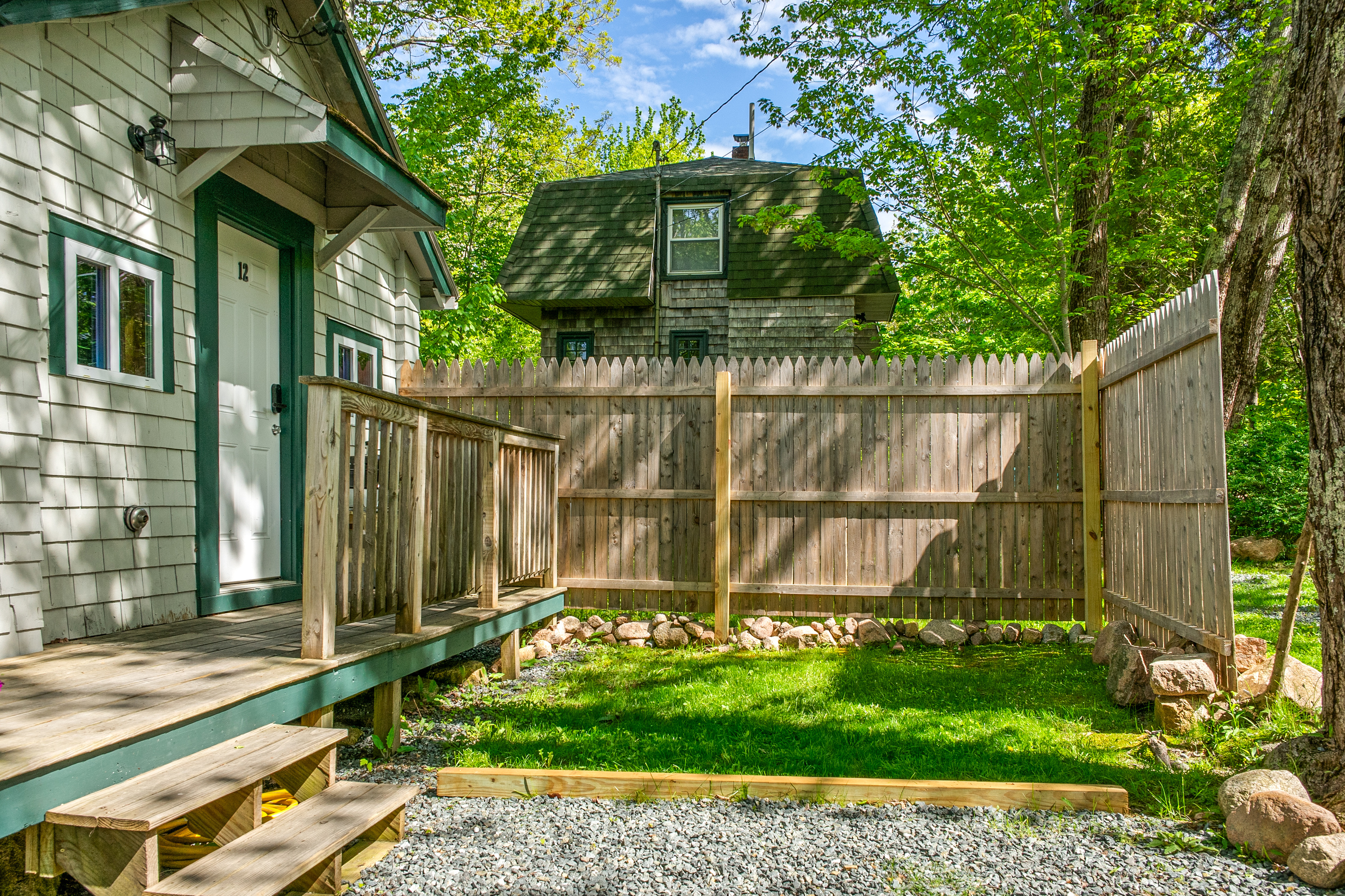 The front deck and a partially fenced, grassy outdoor area. A private, pet-friendly yard space surrounded by summer trees, perfect for your dog to stretch their legs. Relax outside and soak up the fresh island air at the Davis Outpost.