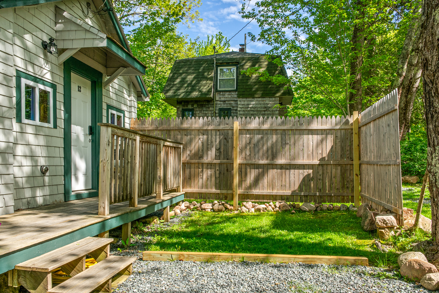 The front deck and a partially fenced, grassy outdoor area. A private, pet-friendly yard space surrounded by summer trees, perfect for your dog to stretch their legs. Relax outside and soak up the fresh island air at the Davis Outpost.