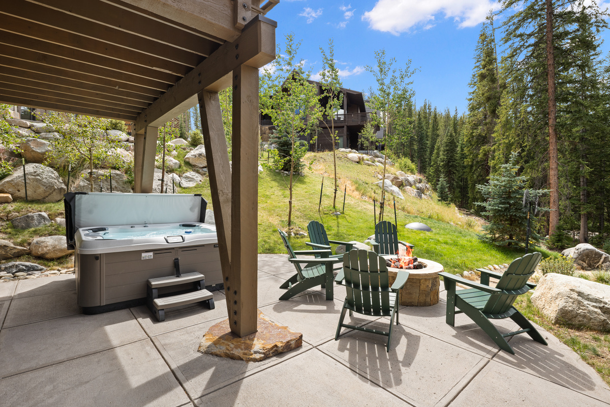 Partially covered private hot tub and gas fire pit with Adirondack lounge chairs. 