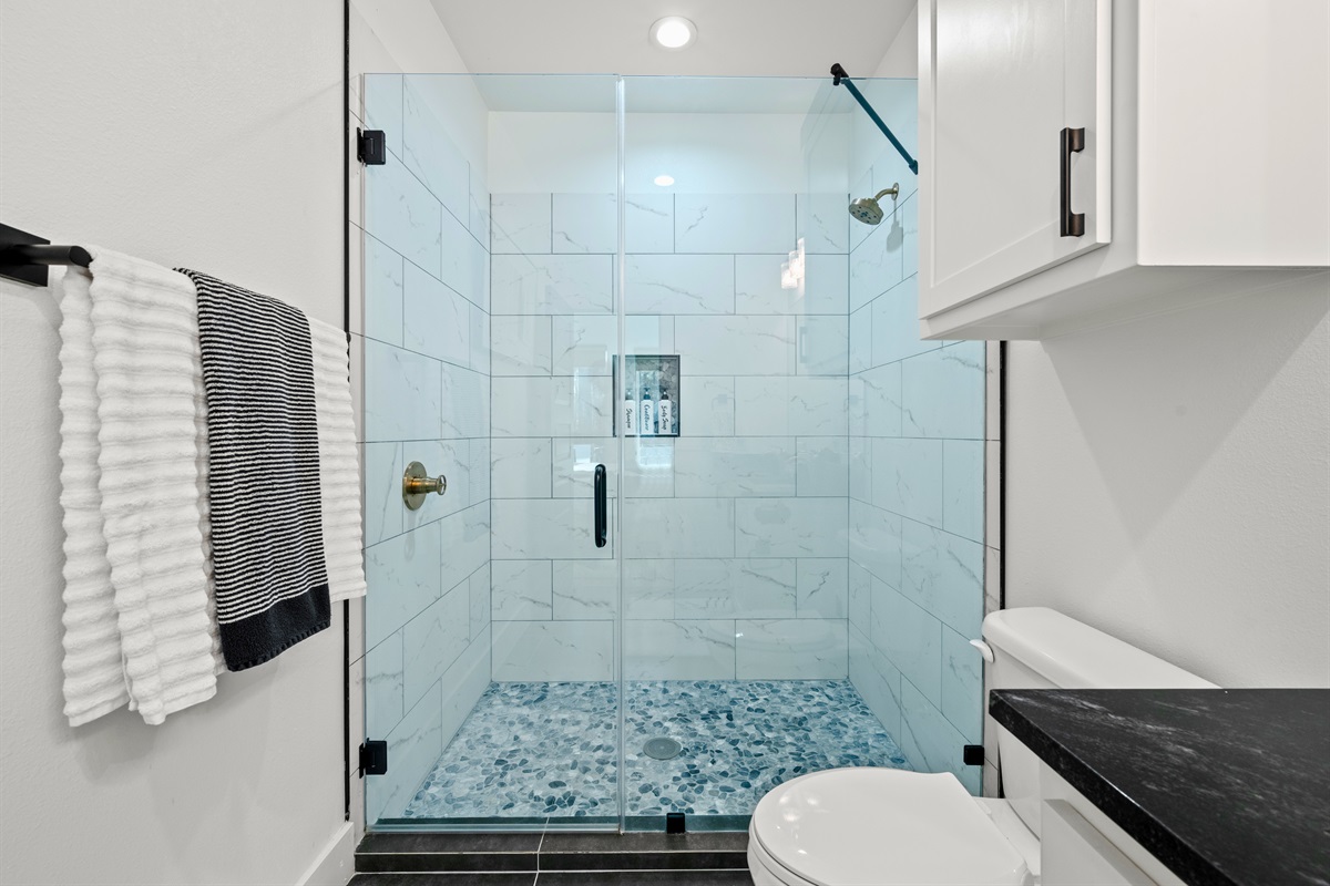 Crisp tilework and glass doors give the shower a bright, polished look that feels both fresh and relaxing.