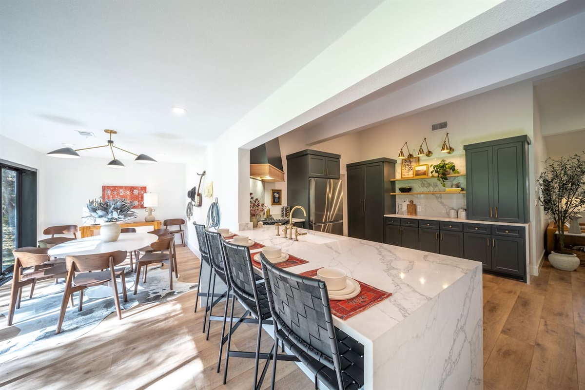 Open dining area connecting the kitchen and living spaces, featuring a large dining table, statement lighting, and a layout designed for gathering, conversation, and shared meals.