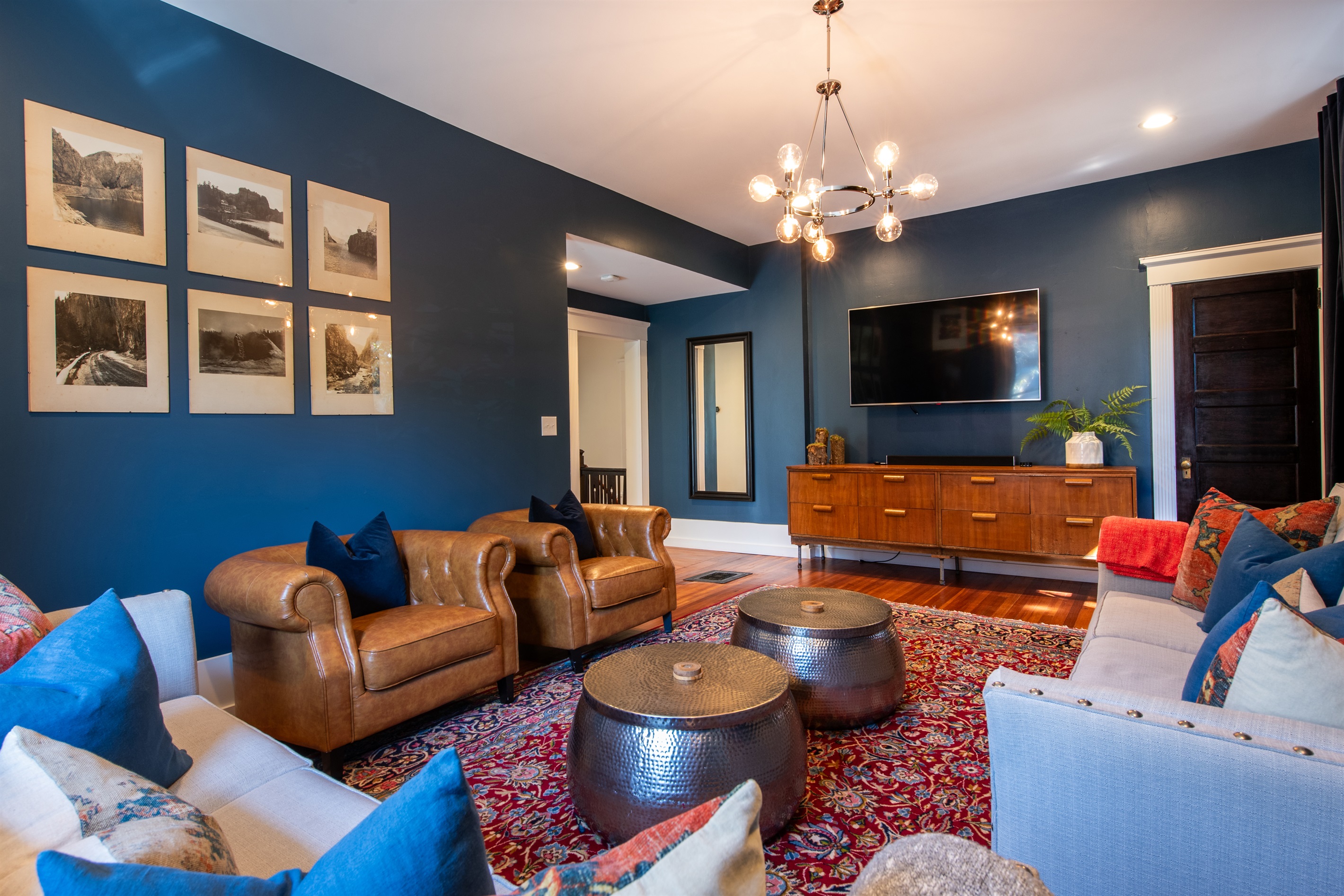 Relax in this chic living room on the Bourbon Trail in Louisville’s Highlands! Features leather chairs, two sofas that pull out to beds, a 75 inch TV, and vintage art—perfect for unwinding. 