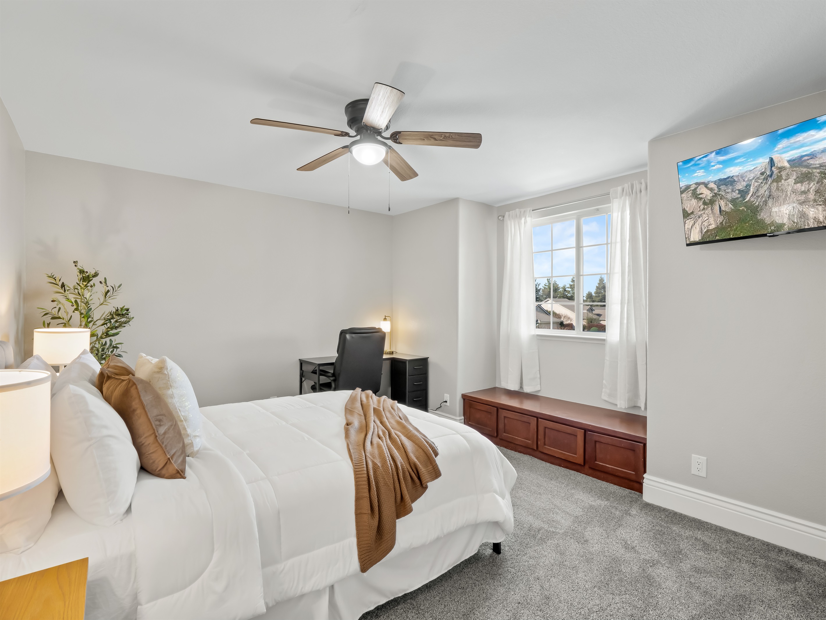 Spacious bedroom with plush carpeting, mounted TV, and a dedicated desk area—perfect for relaxing, working, or streaming your favorite shows.