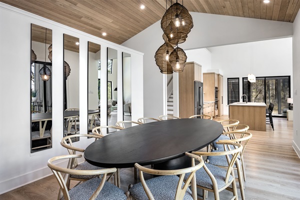Gather your group around the large dining table with views of the outdoor deck and woods beyond—perfect for shared meals and memories.