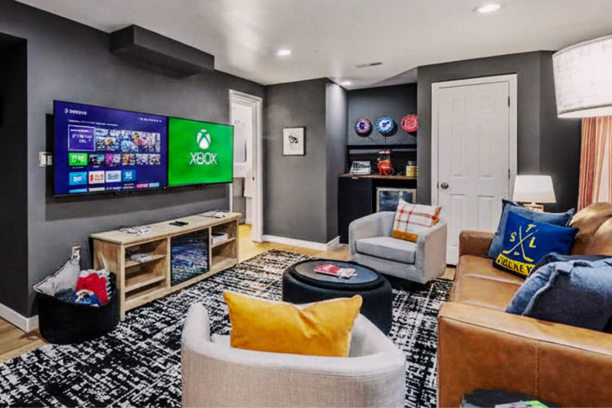 Another view of the entertainment zone featuring dual smart TVs with gaming consoles including an XBox Series S and classic Super Nintendo system. Also enjoy complimentary popcorn and keep drinks cold in the snack bar fridge.