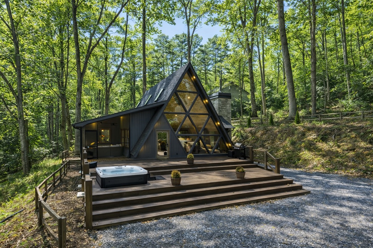 Unwind beneath towering trees in this one-of-a-kind A-frame, featuring expansive decks, glowing interiors, and total tranquility.