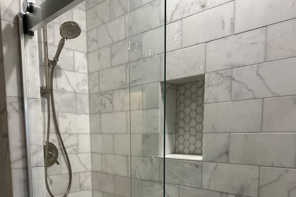 First-floor king suite bathroom with double vanity and marble shower with sliding glass door.